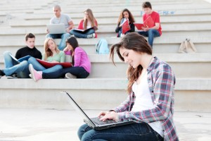 students working with laptops and books on campus